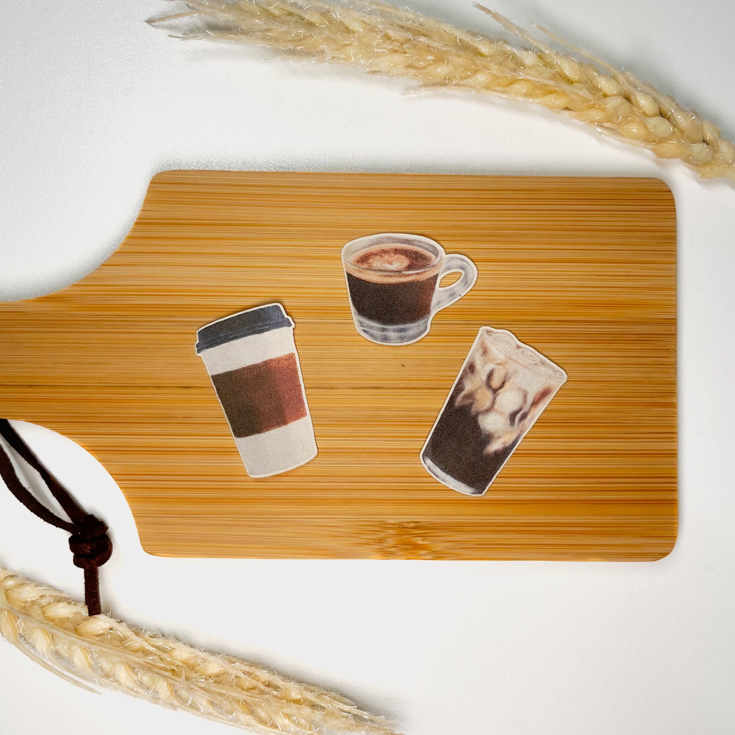 3 Mini Coffee Stickers featuring hand drawn Espresso, Iced Coffee, and a To-Go Cup sitting on a mini wooden charcuterie board on top of a white background