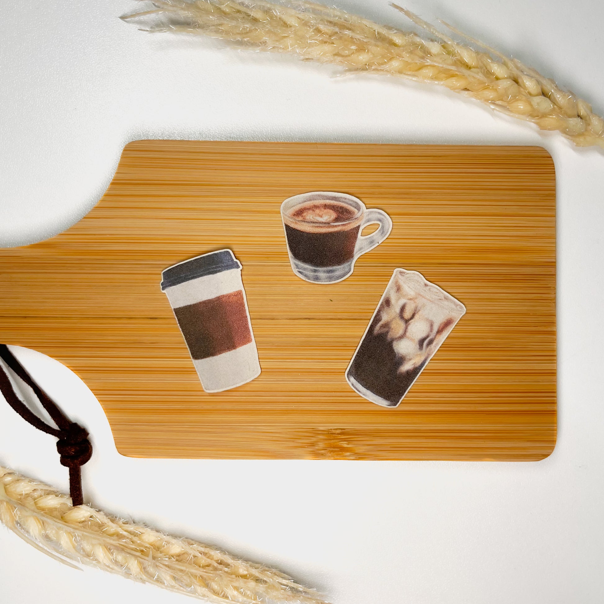 3 Mini Coffee Stickers featuring hand drawn Espresso, Iced Coffee, and a To-Go Cup sitting on a mini wooden charcuterie board on top of a white background