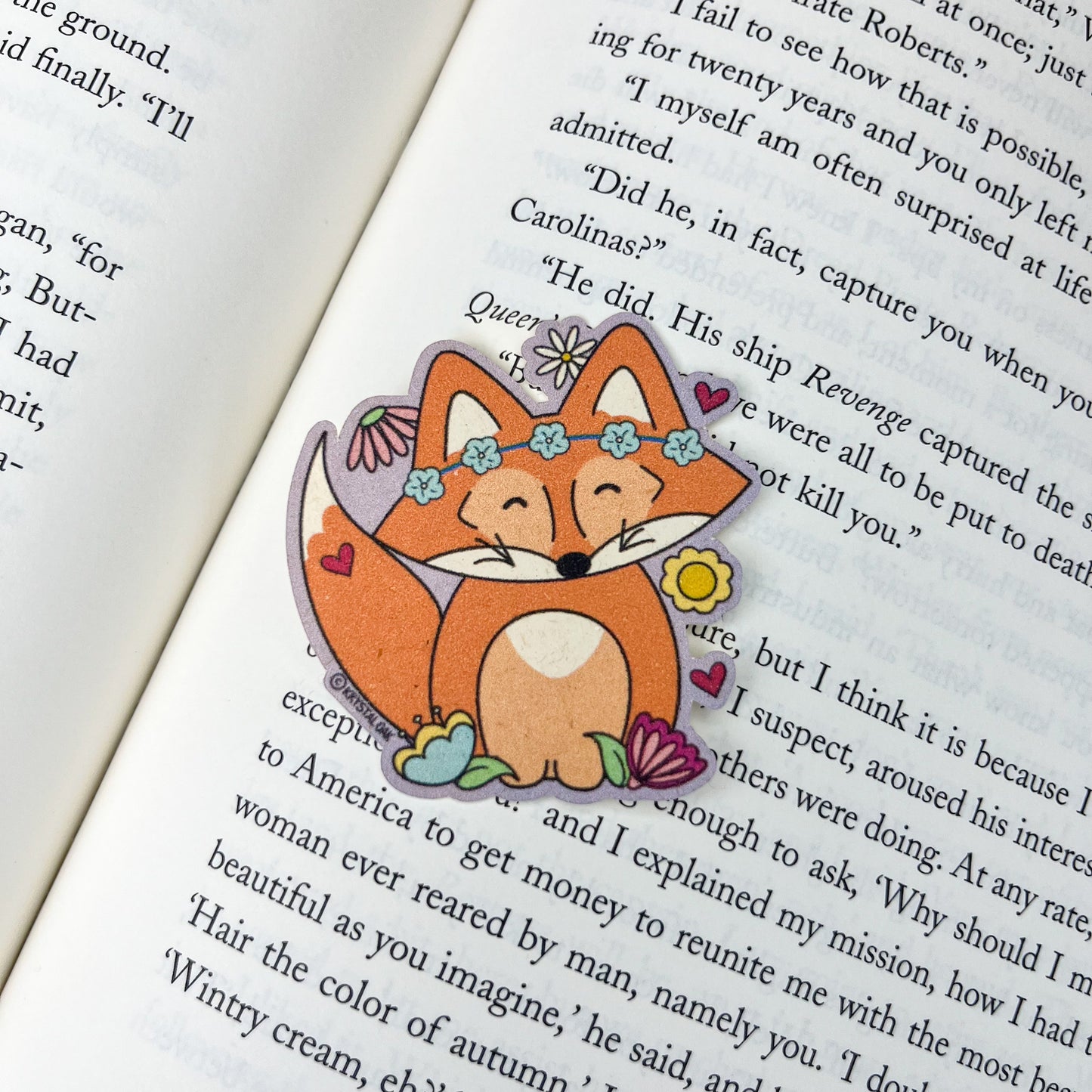 Fox-shaped sticker with floral design on a book page